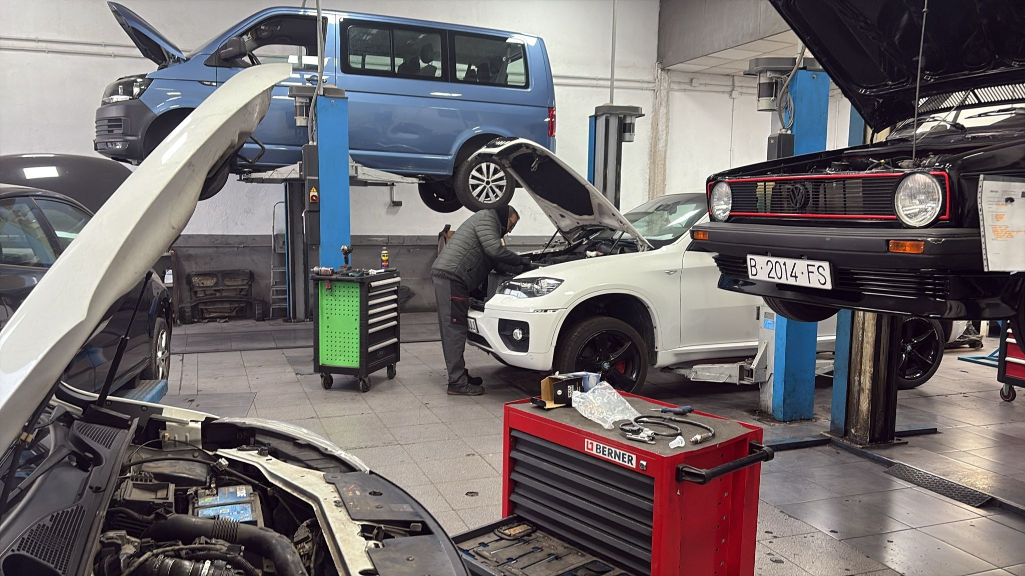 Mecánico trabajando en un vehículo entre los elevadores del taller DIAGMOTOR
